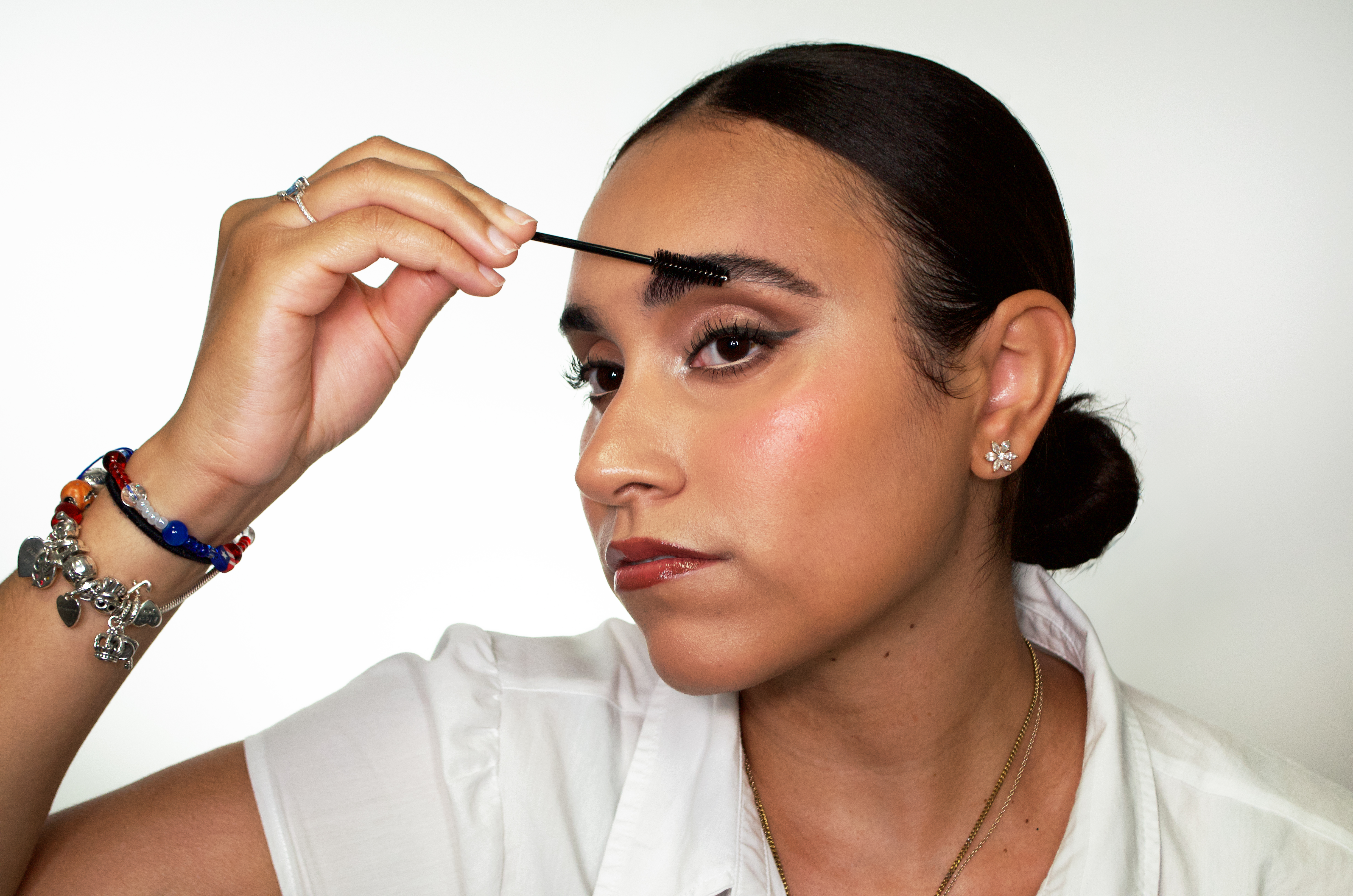side profile of woman using a spoolie brush on her eyebrow 